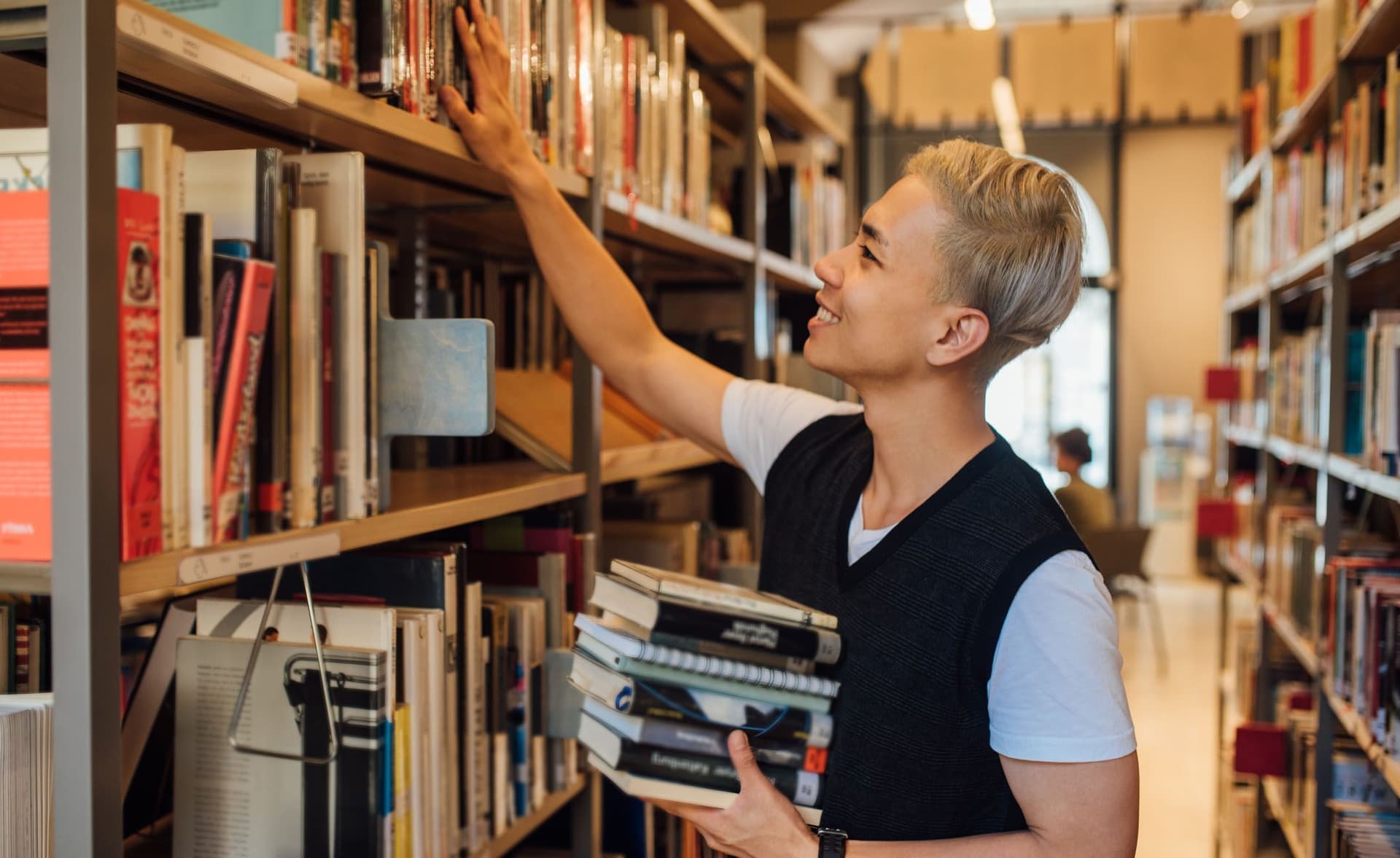 Bibliothekar sortiert Bücher ins Regal ein.