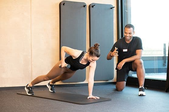 Eine Frau beim Sport und ein Fitnesstrainer.