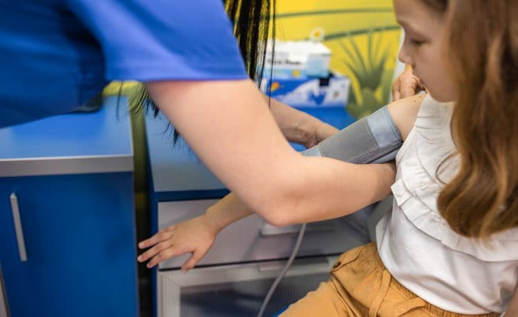 Kinderkrankenpflegerin misst Blutdruck bei einem Mädchen