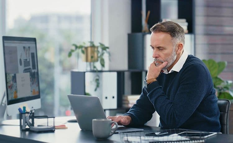 Steuerberater sitzt im Büro und erstellt eine Steuererklärung für einen Mandanten.
