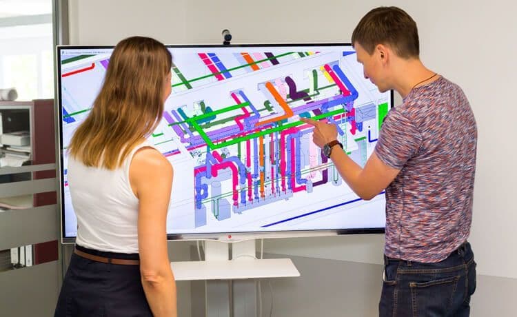 Zwei Studierende stehen vor einem Monitor.