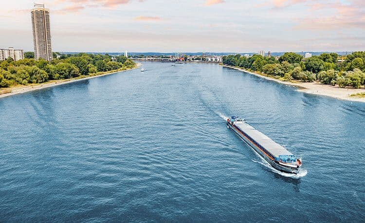 Binnenschiffer fährt mit Frachtschiff über den Rhein bei Köln.