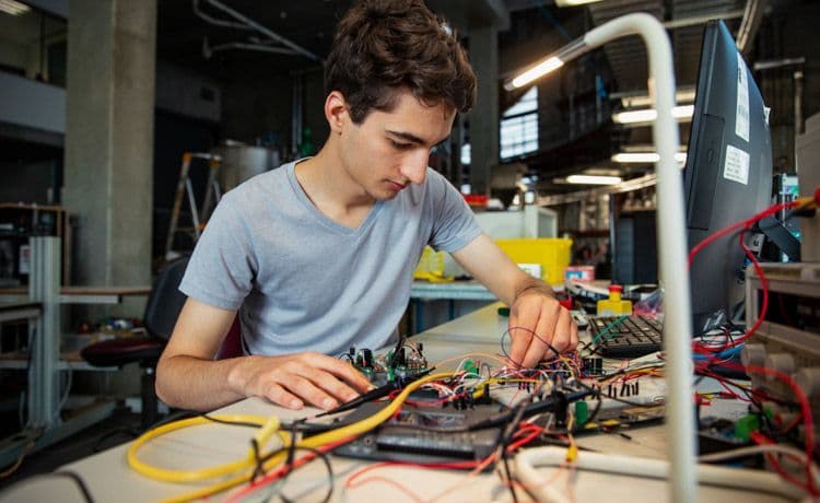 Ein Student im dualen Studium Elektro- und Informationstechnik hantiert mit Stromkabeln.