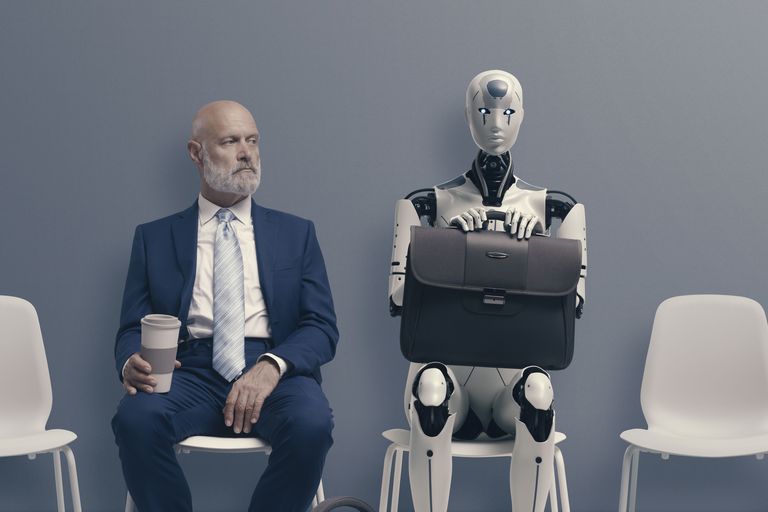 Man sitzt neben Roboter und wartet auf Vorstellungsgespräch.