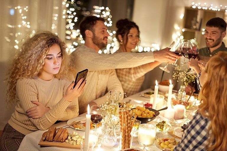 junge Frau ist am Weihnachtstisch am Handy