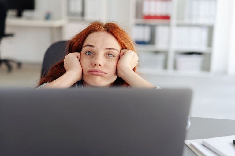 junge Frau langweilt sich am Arbeitsplatz