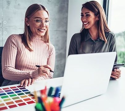 Zwei junge Frauen gucken auf einen Laptop.