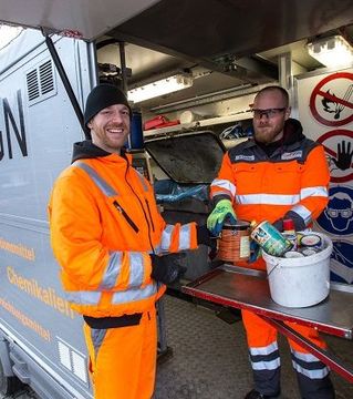 Zwei Mitarbeiter der Müllabfuhr gucken in die Kamera