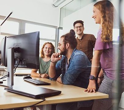 Eine Gruppe von Studierenden steht um einen Computer herum.