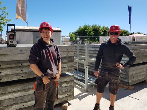 Junge Maurerazubis auf einer Baustelle mit Schutzhelm