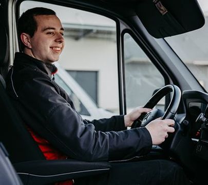 Junger Mann sitzt am Steuer eines Transporters.