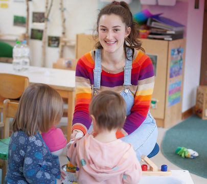 Erzieherin spielt mit zwei Kindern.