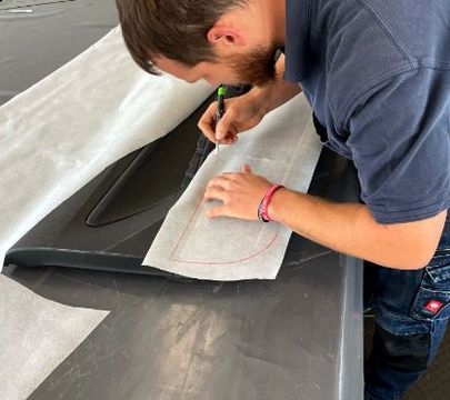 Ein Autosattler zeichnet Formen in Stoff vor.
