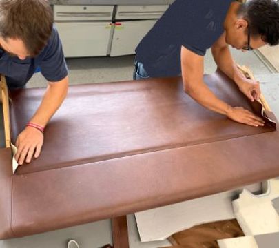 Zwei Autosattler arbeiten an einem Bezug einer Autotür.