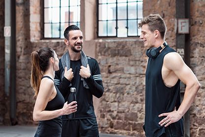 Drei junge Leuten stehen zusammen in Fitnesskleidung.