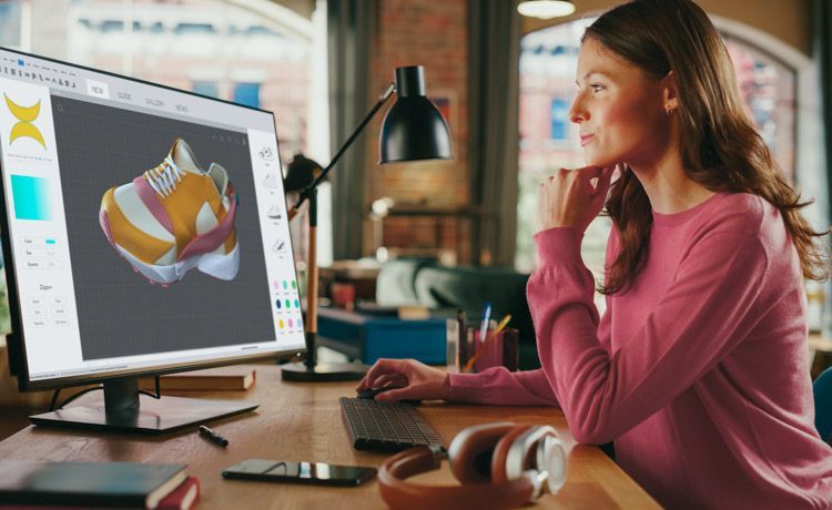 Eine junge 3-D-Designerin arbeitet am Computer an einem 3-D-Modell eines Turnschuhs. Eine junge 3-D-Designerin arbeitet am Computer an einem 3-D-Modell eines Turnschuhs.