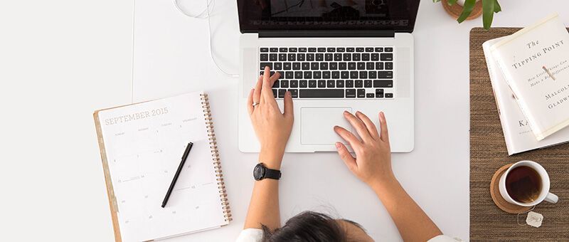 Junge Frau sitzt am Schreibtisch und lernt mit einem Laptop für die Prüfung