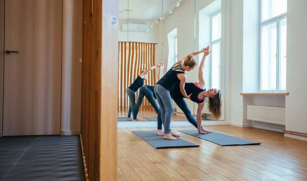 Gymnastiklehrerin hilft einer Schülerin beim Stretching.