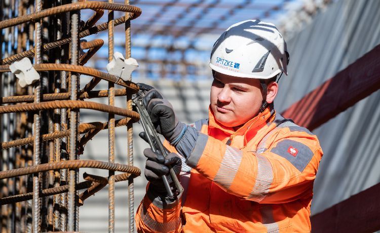 Stahlbetonbauer arbeitet in Schutzkleidung mit einer Zange an verrostetem Stahl, Stahlbetonbauer arbeitet in Schutzkleidung mit einer Zange an verrostetem Stahl,