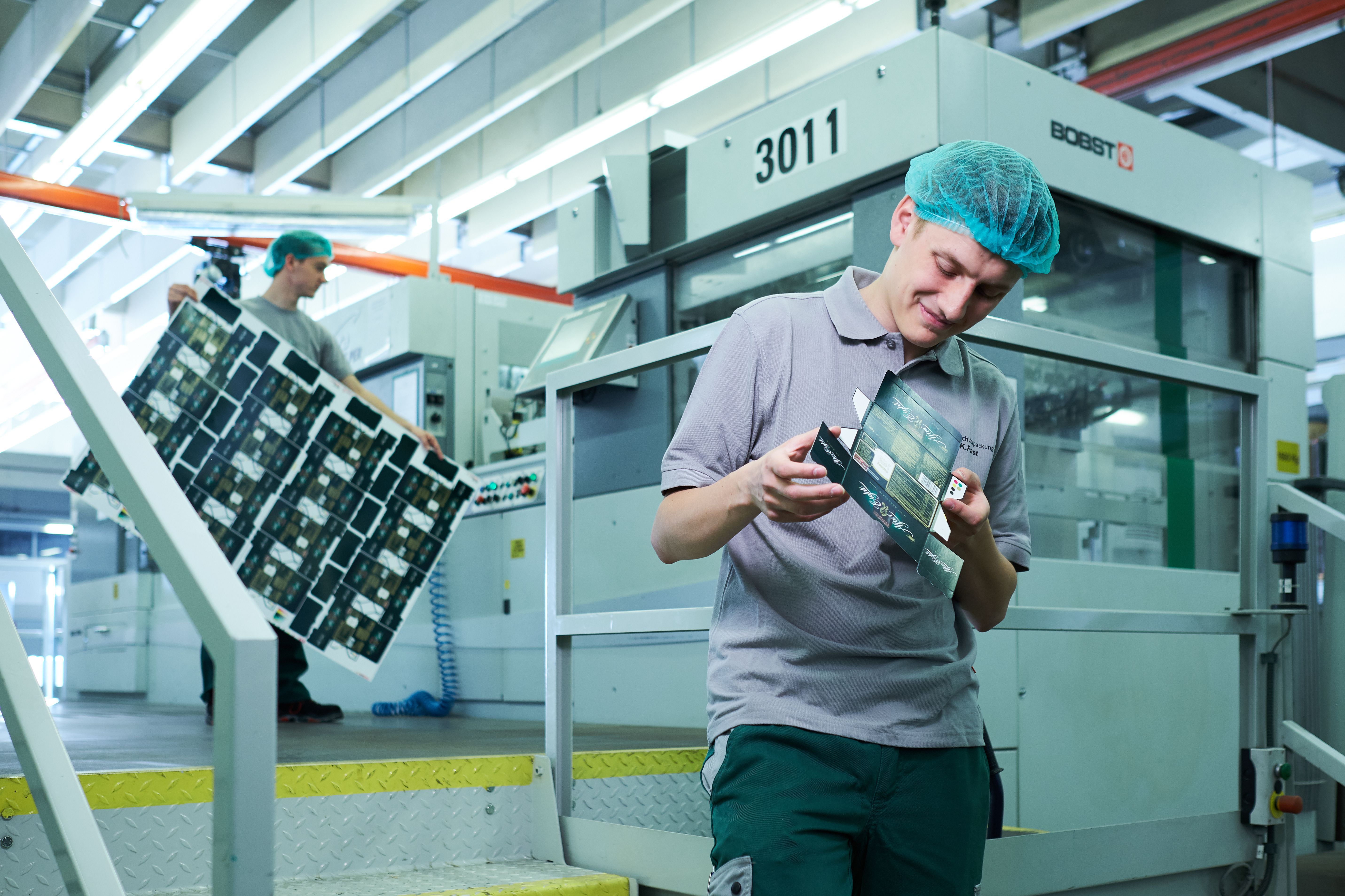 Junger Mann steht in einer Produktionshalle. Junger Mann steht in einer Produktionshalle.