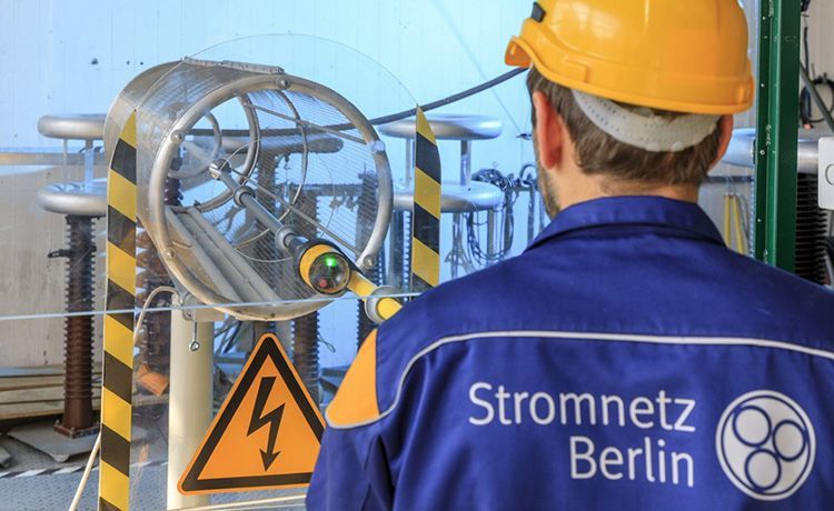 Mann mit einem Helm steht in einem Stromumspannwerk.
