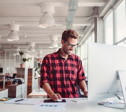Junger Mann steht vor einem Computerbildschirm. Junger Mann steht vor einem Computerbildschirm.