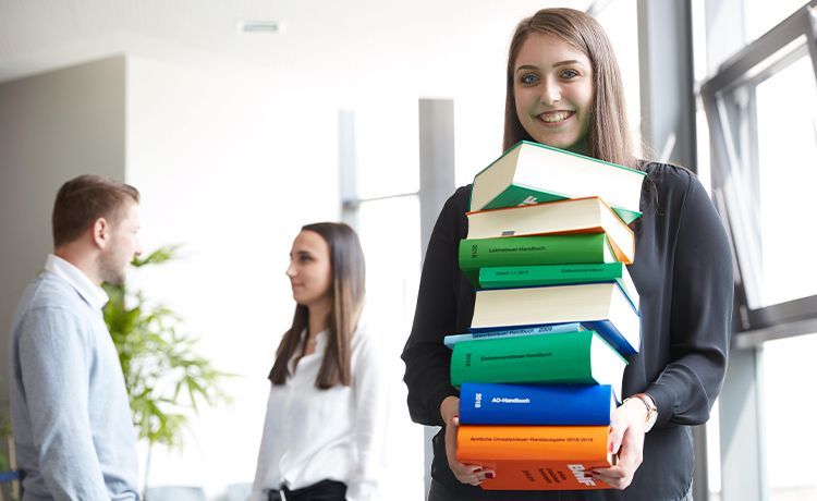 Mädchen hält einen Stapel Bücher in der Hand.