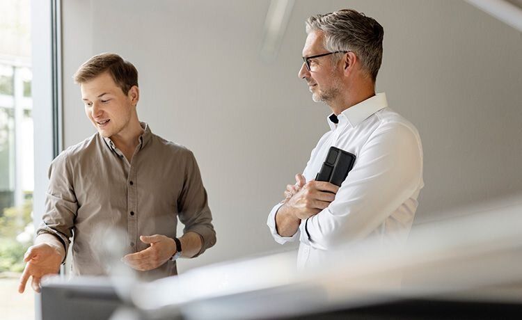 Zwei Männer unterhalten sich in einem Seminarraum. Zwei Männer unterhalten sich in einem Seminarraum.