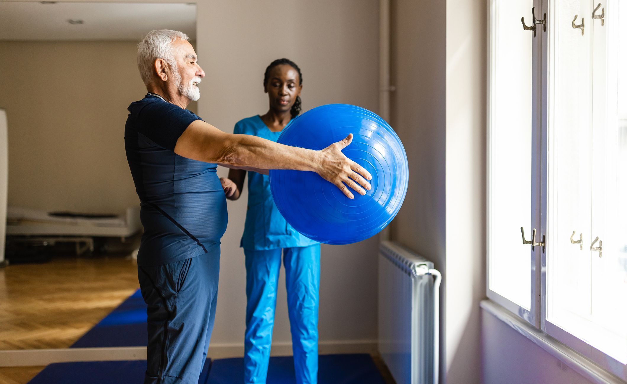 Ergotherapeutin betreut Mann mit Gymnastikball.
