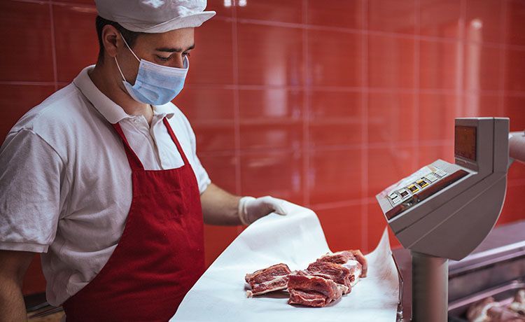 Fleischer wiegt mehrere Stücke Fleisch ab.