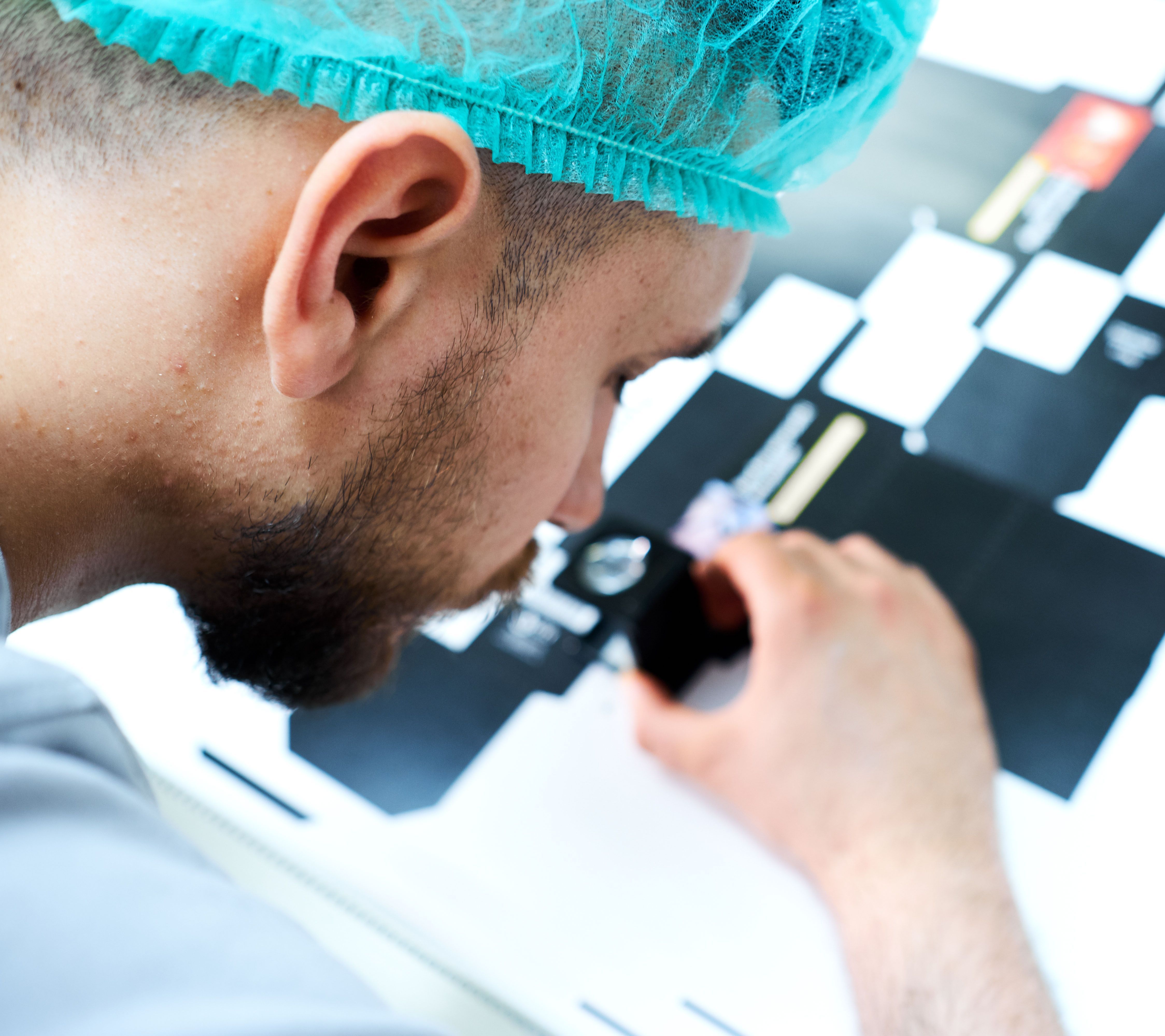 Ein Mann begutachtet etwas mit einer Lupe. Ein Mann begutachtet etwas mit einer Lupe.