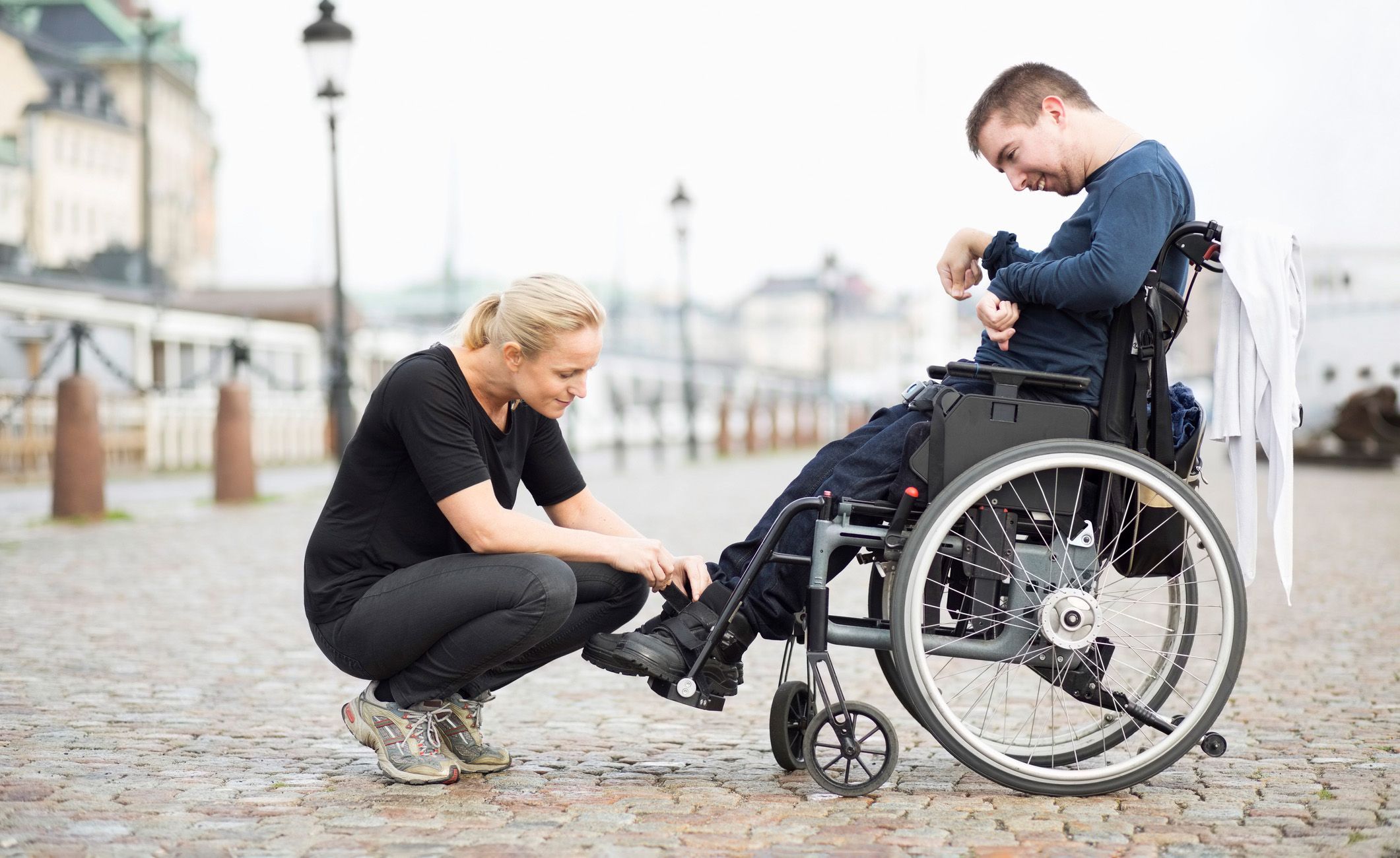 Heilerziehungsplfegerin bindet den Schuh von einem Patienten zu, 