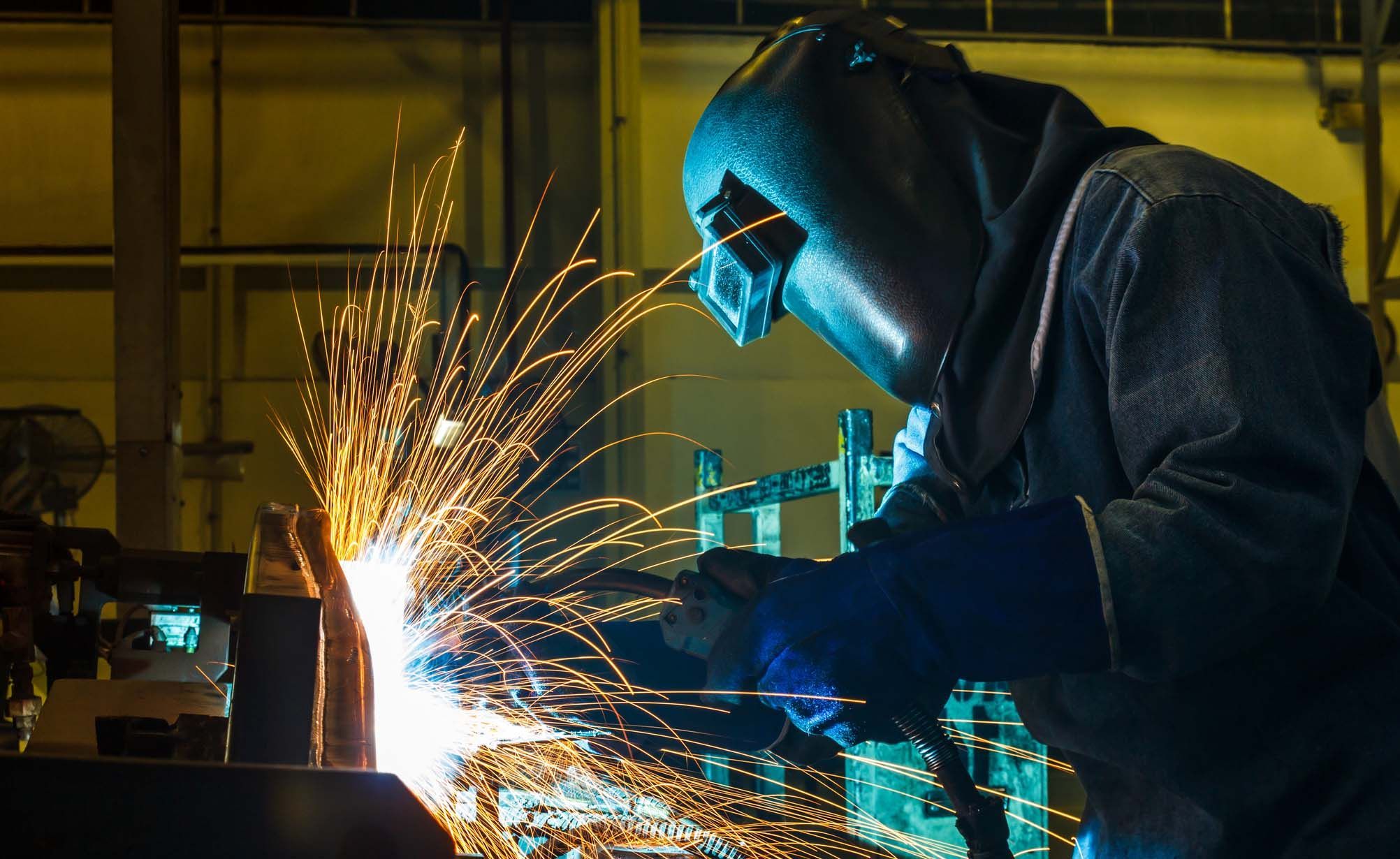 Ein Konstruktionsmechaniker schweißt Metall in Schweißerausrüstung.