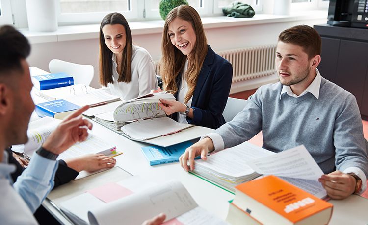 Studierende lernen für eine Prüfung an einem Tisch mit Büchern.