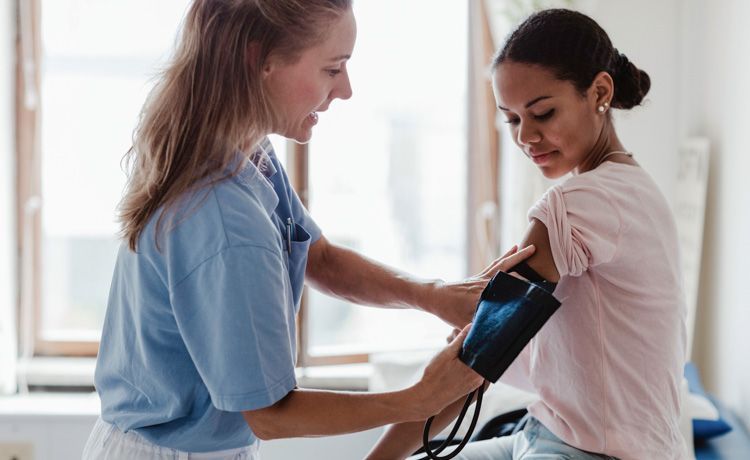 Eine MTF misst bei einer jungen Patientin den Blutdruck.