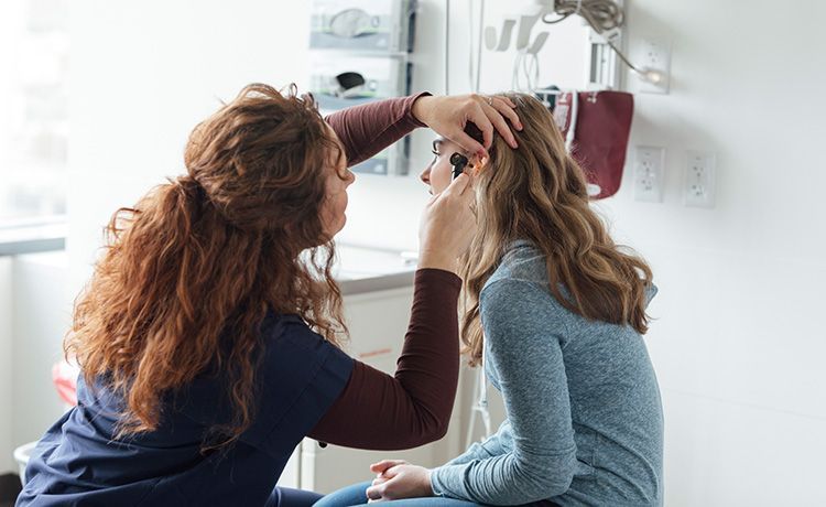 Eine Medizinische Technologin für Funktionsdiagnostik untersucht das Ohr eines Mädchens.