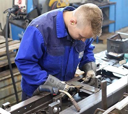 Ein Azubi arbeitet in einer Werkstatt an einem Stück Metall.