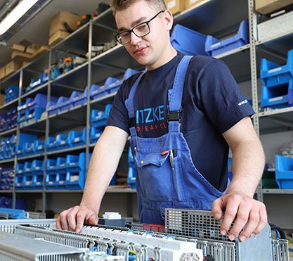 Azubi in Arbeitskleidung arbeitet an einem Gerät.