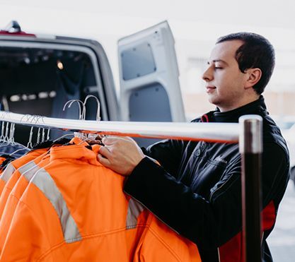 Junger Mann räumt Kleidung in einen Transporter.