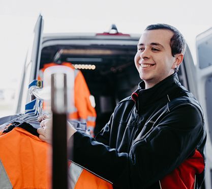 Junger Mann steht vor einem Transporter.
