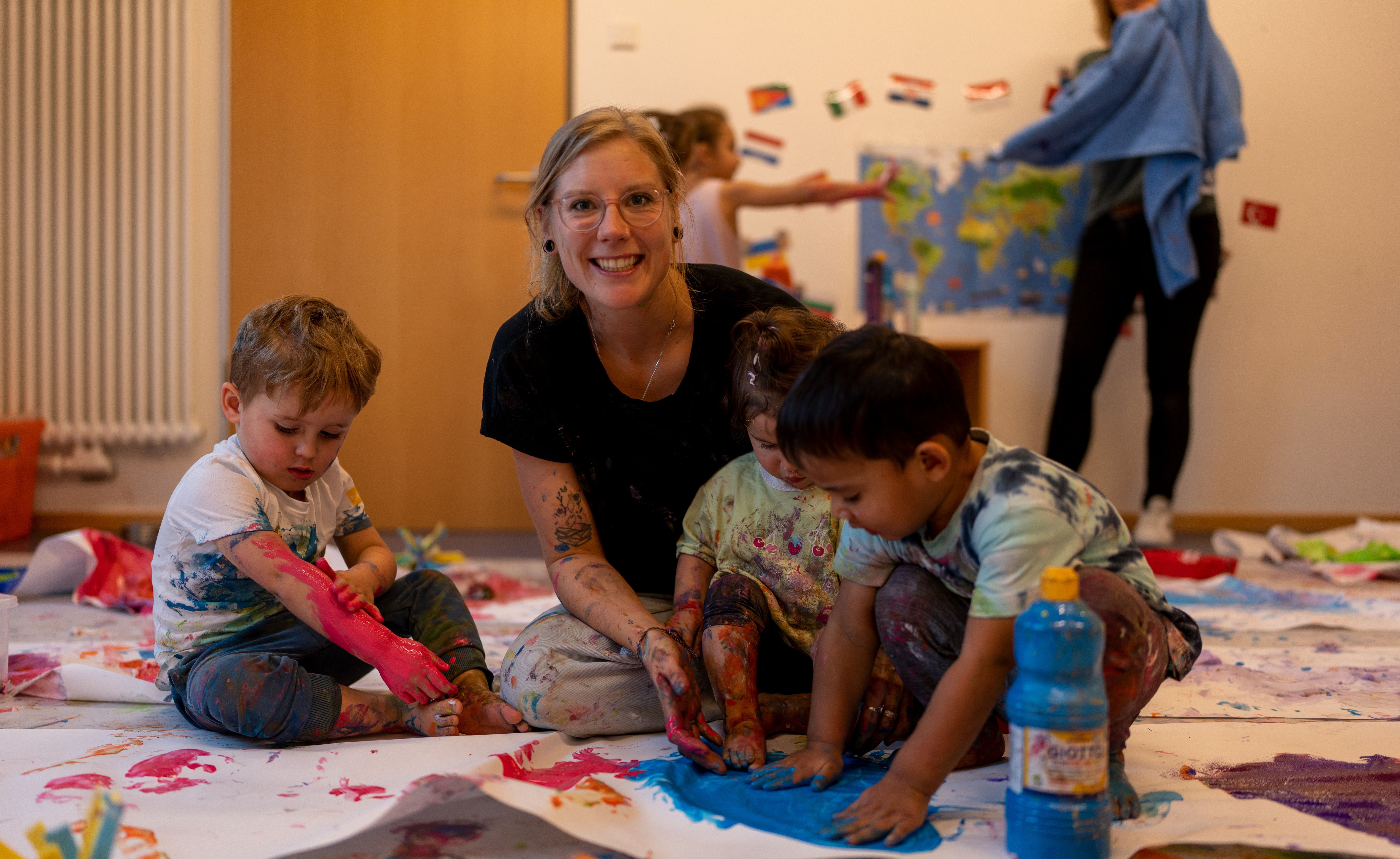 Erzieherin malt mit drei Kindern. Erzieherin malt mit drei Kindern.