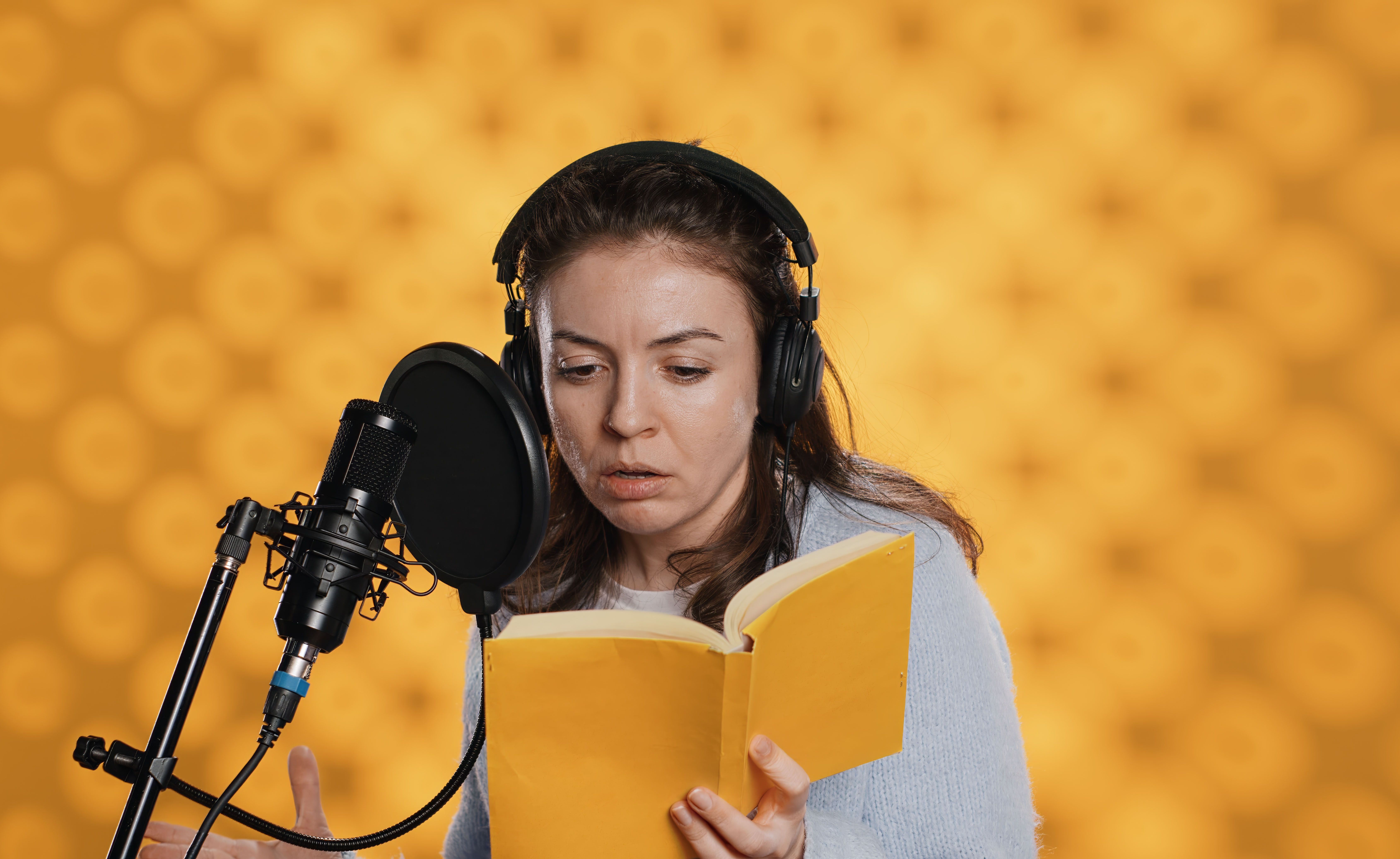 Frau liest aus einem Buch vor einem Mikrofon vor