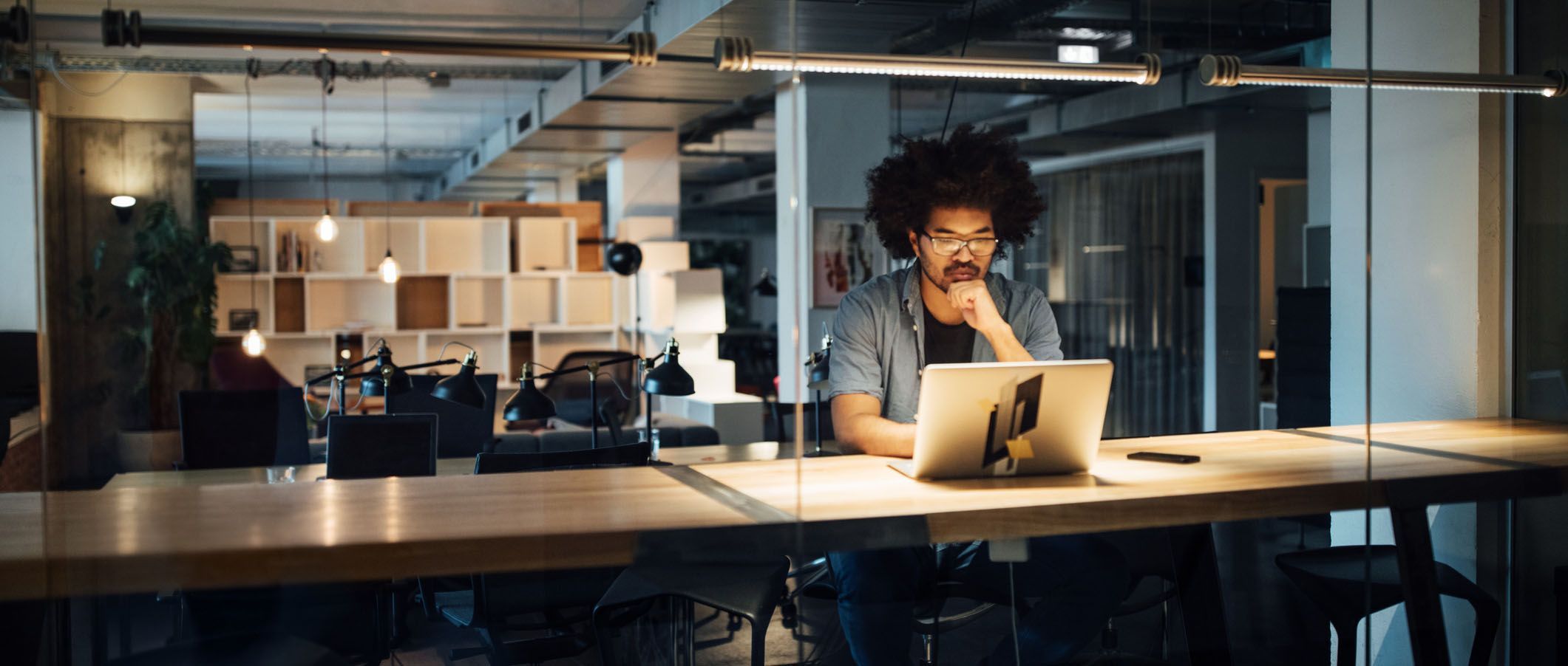 Azubi sitzt alleine im Dunkeln im Büro und macht Überstunden. Azubi sitzt alleine im Dunkeln im Büro und macht Überstunden.