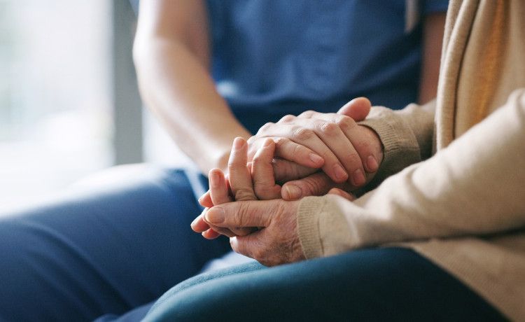 Altenpflegerin hält die Hand einer Patientin.
