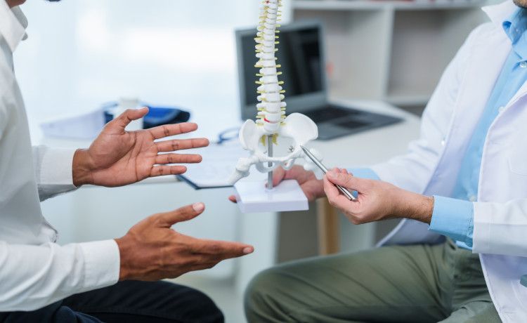Orthopäde erklärt Patienten den Aufbau der Wirbelsäule. Orthopäde erklärt Patienten den Aufbau der Wirbelsäule.