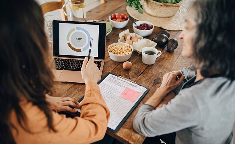 Ernärhungsberaterin sitzt an einem Tisch und berät eine Klienten zu ihren Essgewohnheiten.