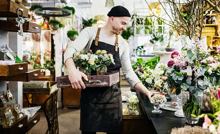 Junger Mann mit Mütze arbeite in einem Blumenladen.