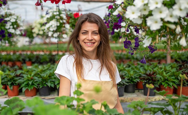Lächelnde junge Frau steht in einem Blumencenter. Lächelnde junge Frau steht in einem Blumencenter.