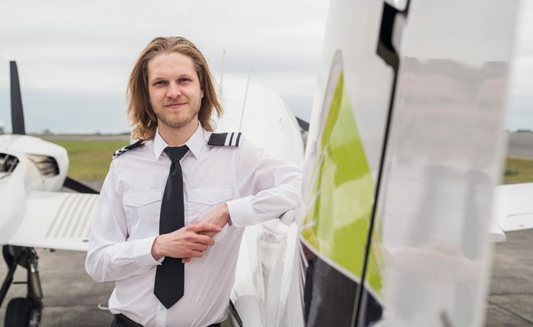 Ein junger Mann lehnt an einem Flugzeug.