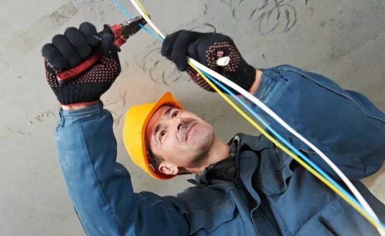 Handwerker schneidet Kabel durch.